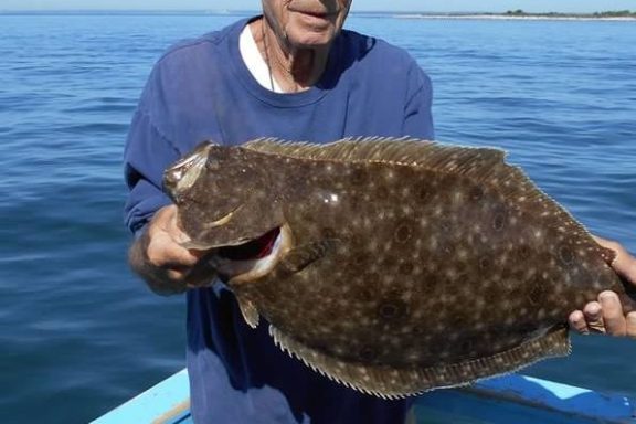 a man holding a fish on a boat in a body of water