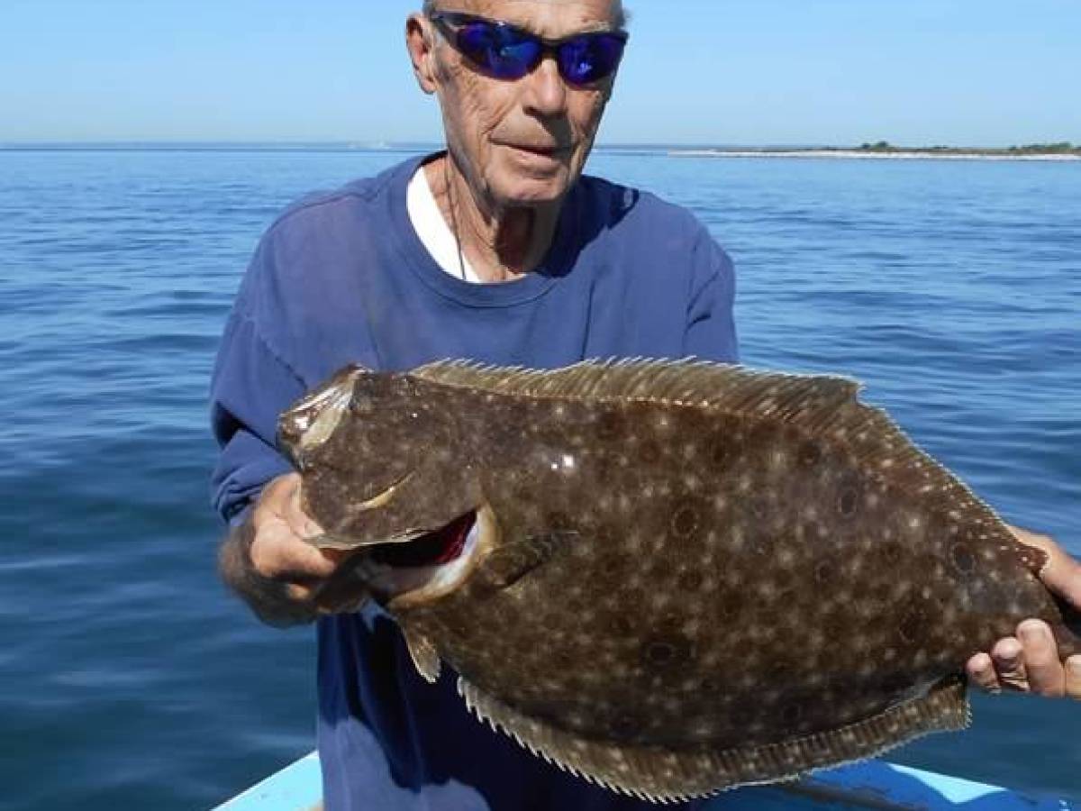 a man holding a fish on a boat in a body of water
