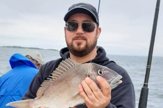 a person holding a fish on a boat in the water