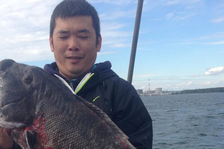 a person holding a fish in front of a body of water