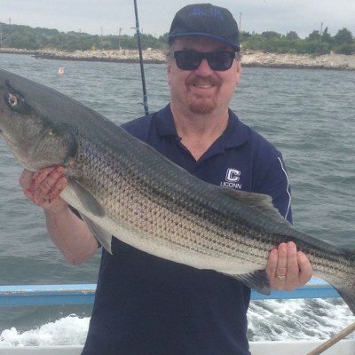a man holding a fish on a boat in a body of water