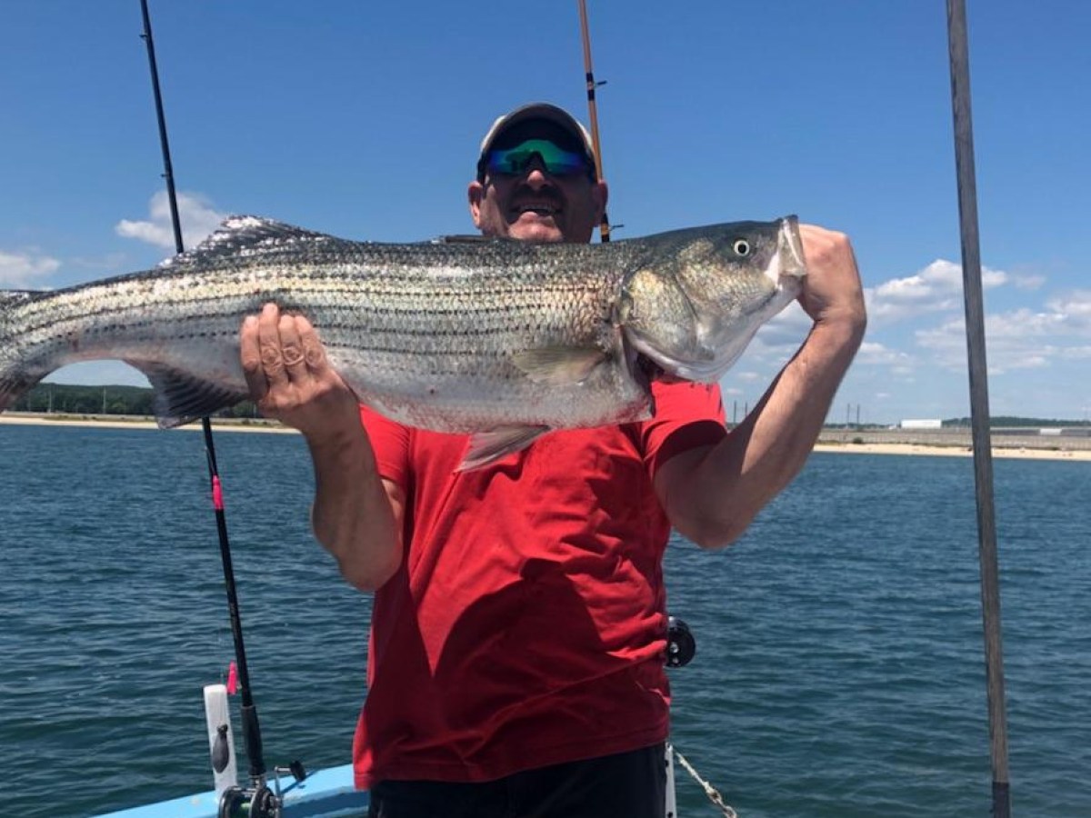 a man holding a fish on a boat in a body of water