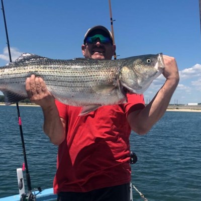 a man holding a fish on a boat in a body of water