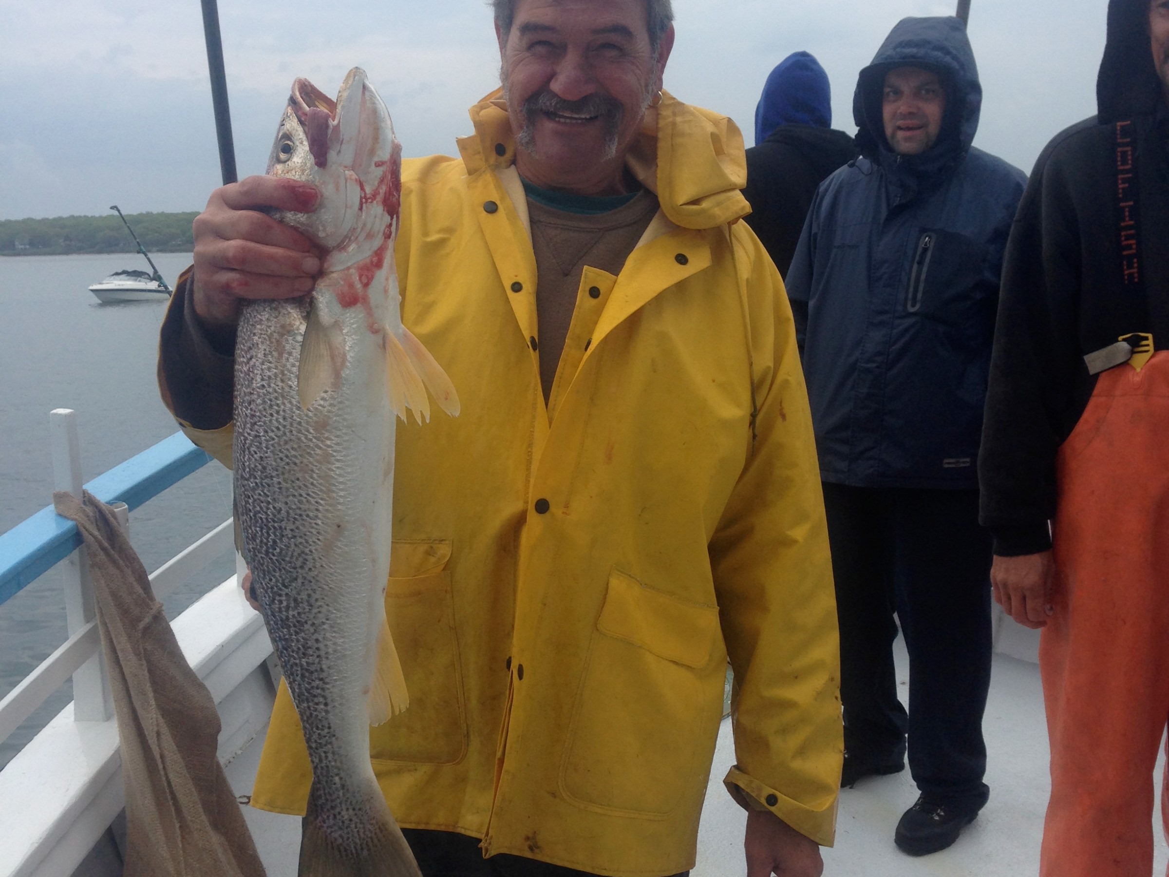 a group of people standing next to a person holding a fish