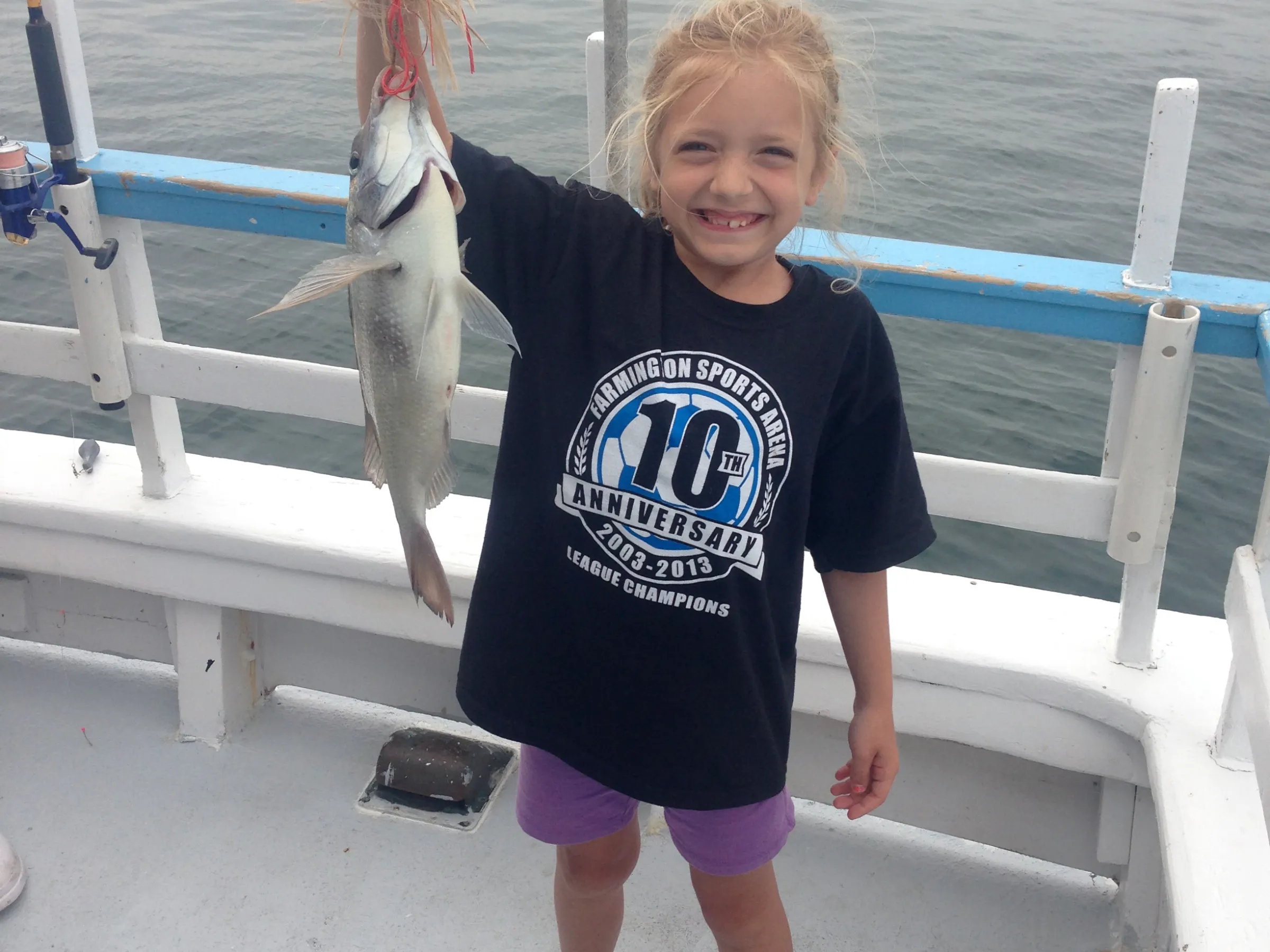 a little girl standing next to a body of water