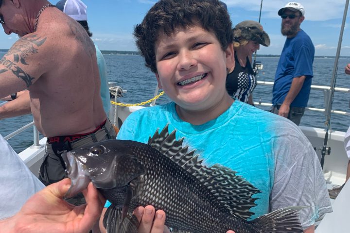 a group of people standing next to a man holding a fish