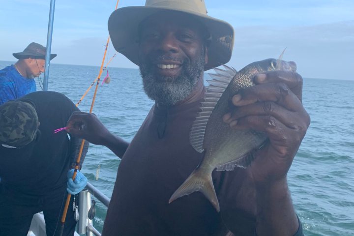 a man holding a fish on a boat