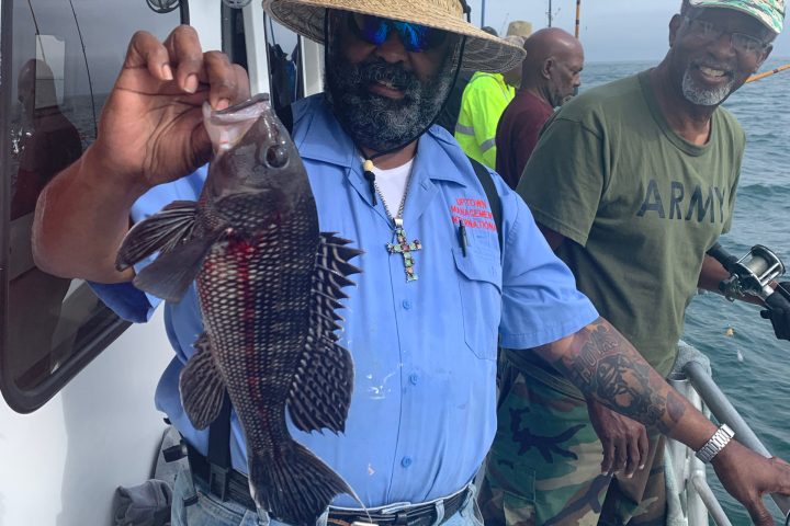 a group of people standing next to a man wearing a hat