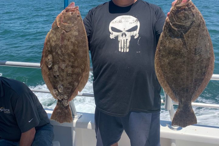 a man holding a fish on a boat in the water